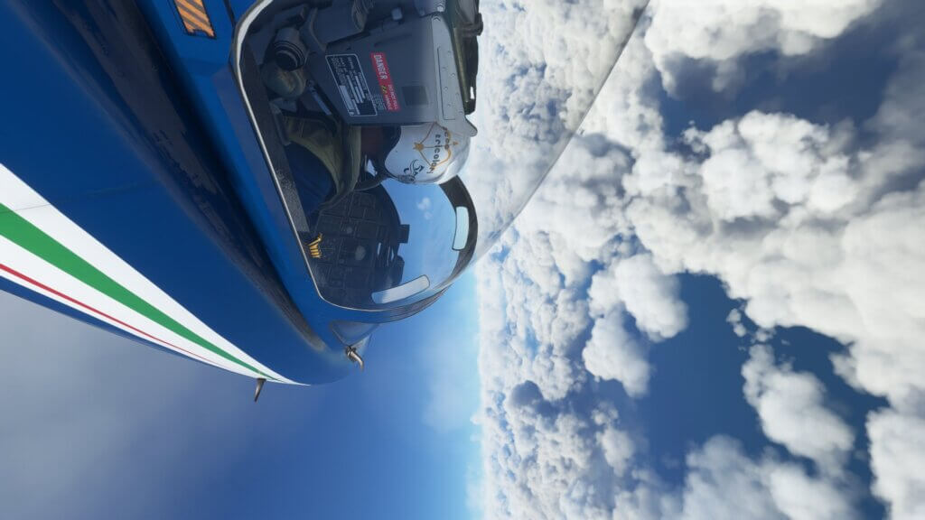 An aircraft flies upside down above the clouds, with the image turned on its side.